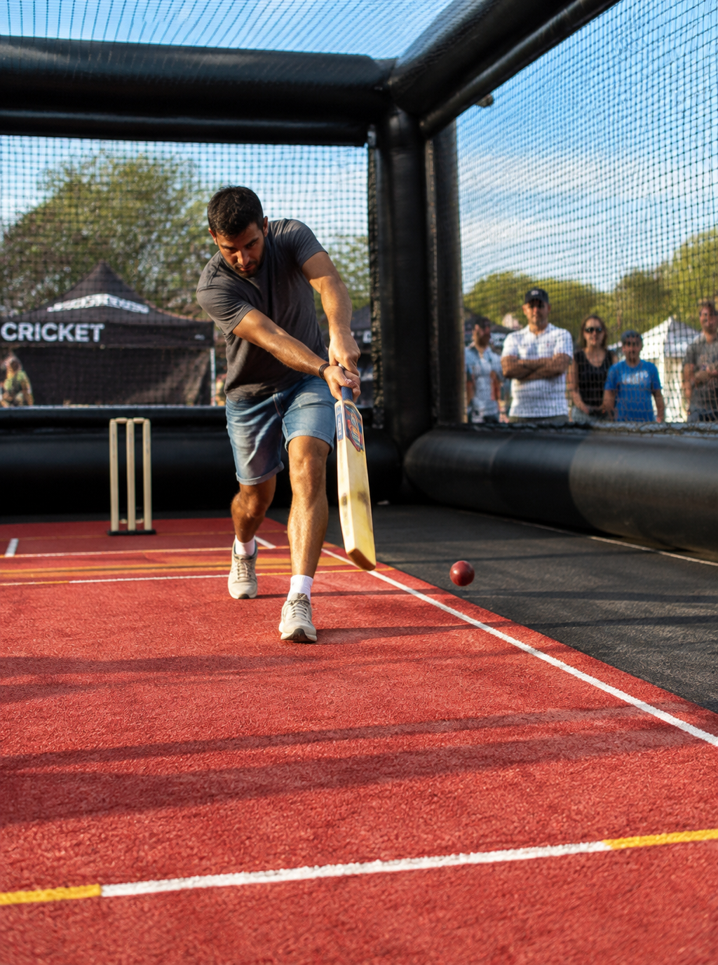 Player batting on a red floor inside an inflatable pop-up cricket simulator